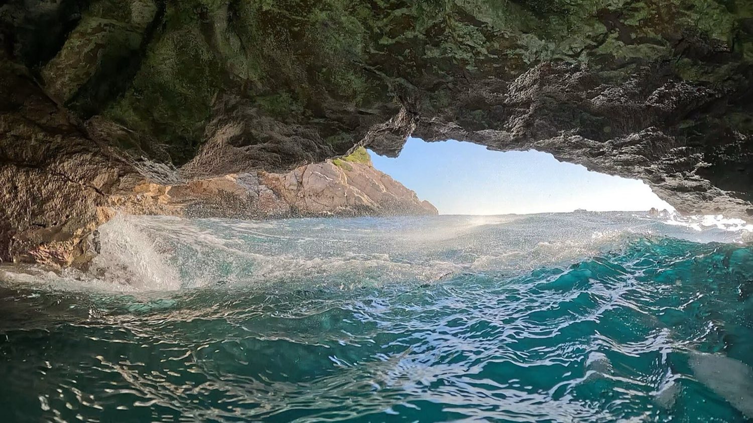 Snorkeller finning over a rocky seabed and seagrass in clear Mediterranean water